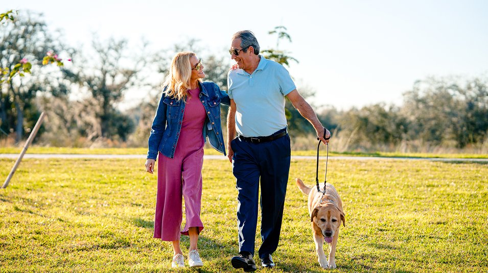 Residents walking a dog on the community green at Valencia Golf & Country Club, Naples FL